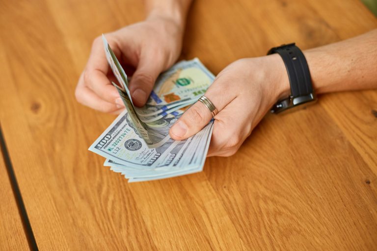 Photo of man counting money illustrates blog "Does Pawning Affect Your Credit Score?"