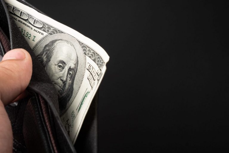 Closeup of hand holding wallet with 100 dollar bill illustrates blog "How Can I Make Cash in One Day?"