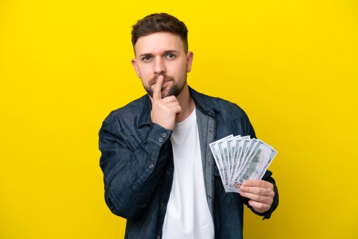 Photo of holding 100-dollar bills illustrates blog "Is It Better To Pawn or To Sell?"