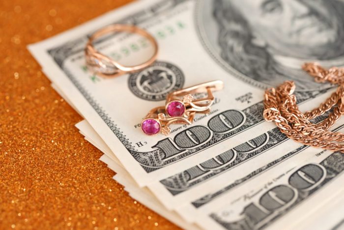 Photo of jewelry placed on top of 100-dollar bills illustrates blog: "How Long Do Pawn Shops Keep Items?"