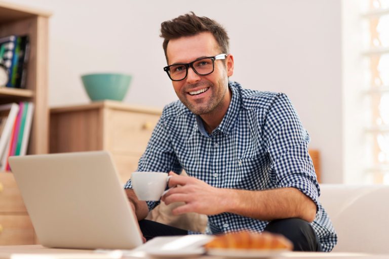Photo of man in living room looking at laptop illustrates blog:; "What Household Items Can I Pawn?"