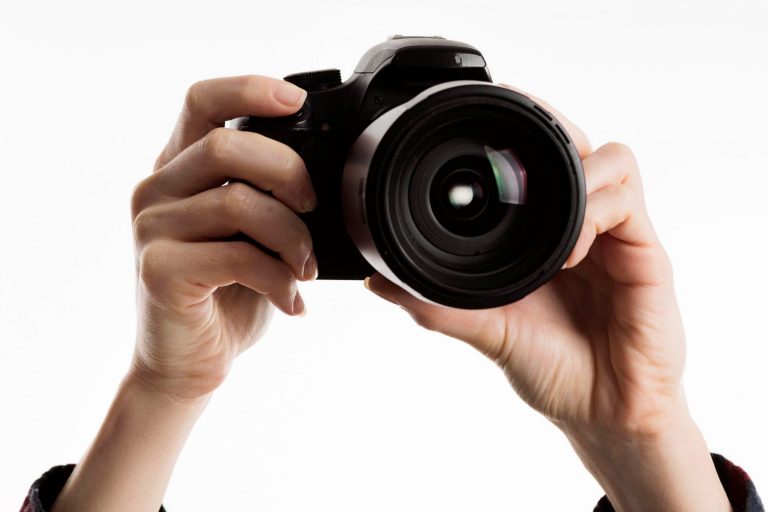 Closeup of hands holding camera illustrates blog "How To Pawn or Sell a Camera or Camera Lens?"