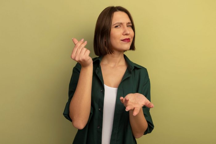Woman making money sign with thumb and index, middle fingers illustrates blog "Pawn Shop vs Banks: When to Use Each"