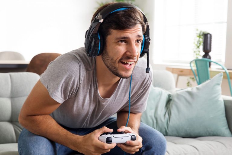 Man leaning forward with headset holding PS5 controller with both hands.