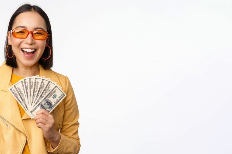 Woman with sunglasses and yellow jacket holding dollar bills illustrates blog "Is Pawning a Loan?"