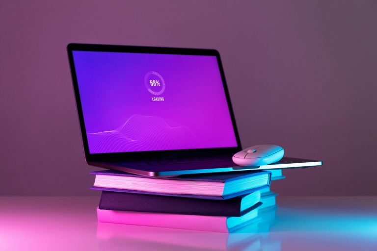 Photo of laptop placed atop a pile of books illustrates blog "Can You Pawn a MacBook?"