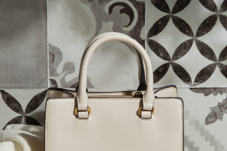 Luxury handbag against background of patterned tiles.