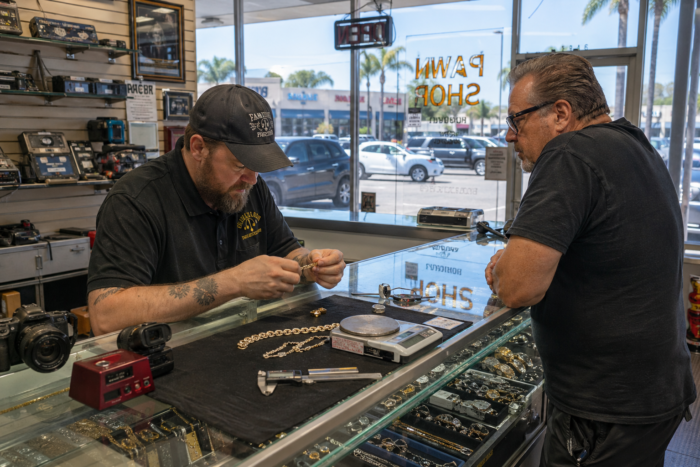 Pawn shop pricing evaluation for jewelry, electronics, and tools at a service counter